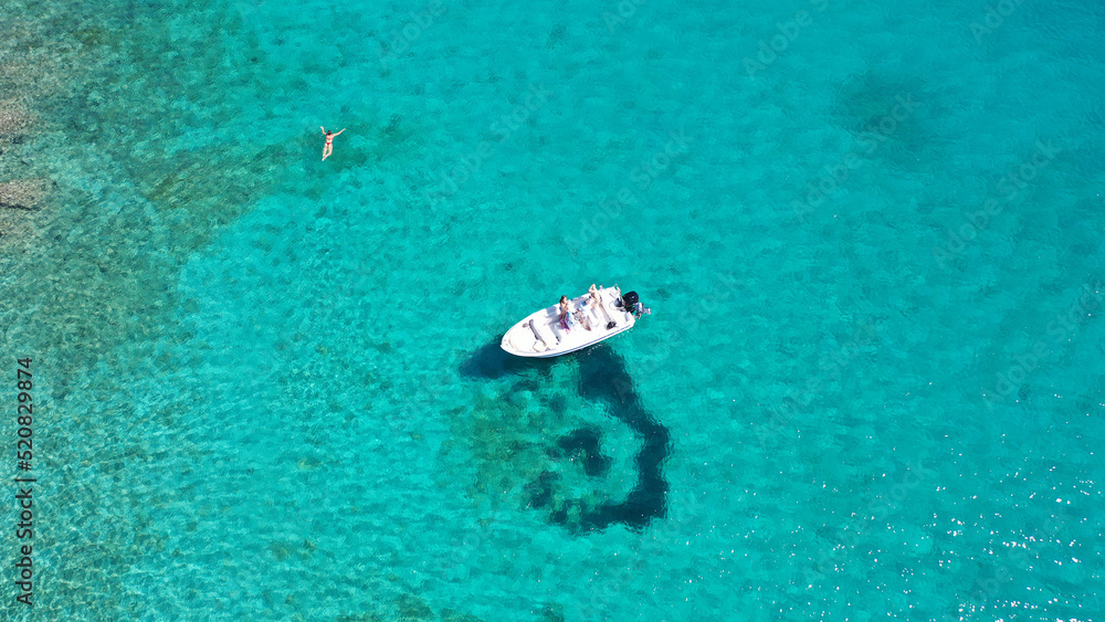 Aerial drone photo of small inflatable boat anchored in tropical Caribbean turquoise bay with calm sea Aerial drone photo of small inflatable boat anchored in tropical Caribbean turquoise bay with calm sea