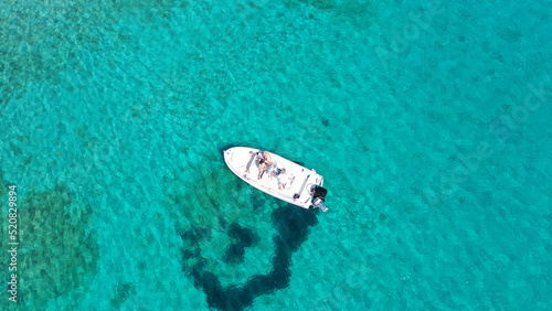 Aerial drone photo of small inflatable boat anchored in tropical Caribbean turquoise bay with calm sea © aerial-drone
