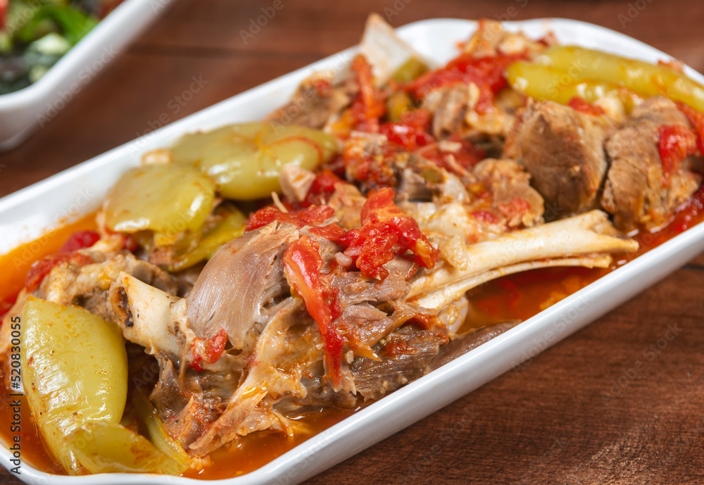stewed lamb on the bone with vegetables on wooden desk.Khashlama is popular Armenian dish, which is prepared from beef with vegetables. Khashlama in the plate.  caucasian food