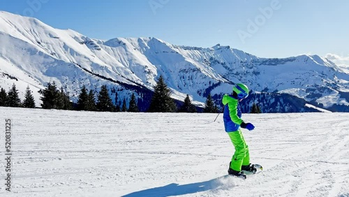 Snowboarder boy go downhill on snowboard from mountain top