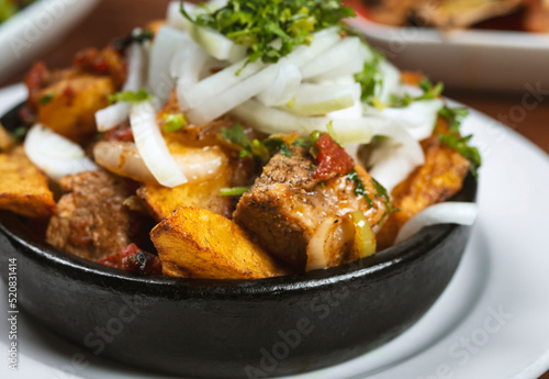 Beef stew with potatoes, carrots and herbs on black background with copy