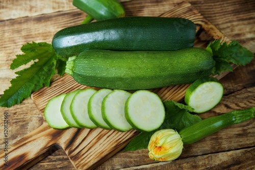 The raw product of zucchini lie on the wooden surface of the table. Ingredients for cooking. Seasonal vegetables.