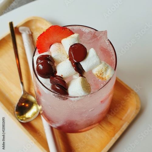 A glass of mixed berries soda with marshmallow and red beans on top