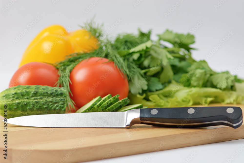 Chopping board with tomato, cucumber, parsley and knife Chopping board with tomato, cucumber, parsley and knife