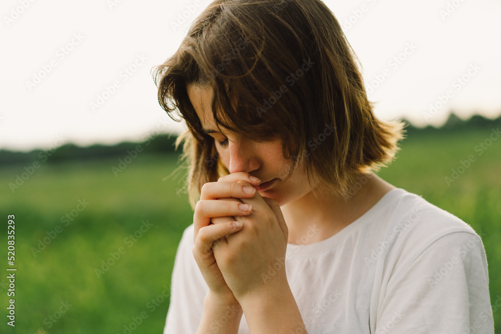 Teenager Girl closed her eyes, praying. Hands folded in prayer concept for faith, spirituality and religion. Peace, hope, dreams concept