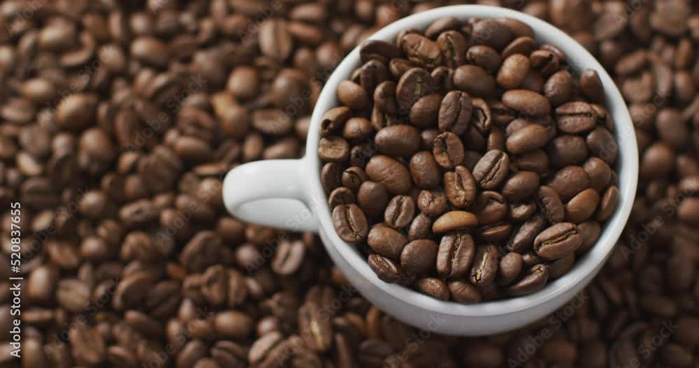 Video of cup of coffee beans over roasted brown coffee beans Video of cup of coffee beans over roasted brown coffee beans