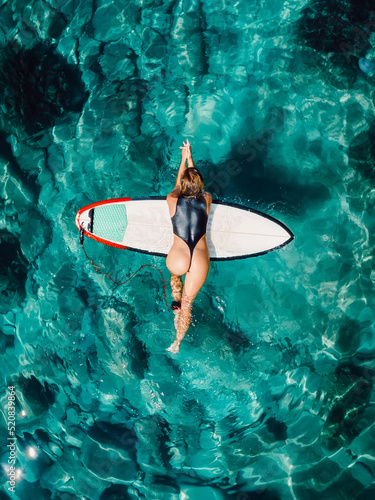 Surf girl in sexy swimsuit with surfboard in transparent sea. Aerial view with beauty surfer woman
