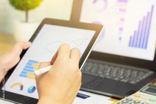 Closeup of female hand writing tablet for data analysis in data graph form.