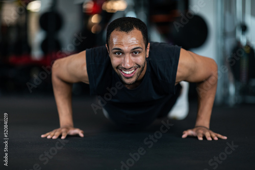 Smiling Handsome Black Man Making Push Up Exercises While Training At Gym