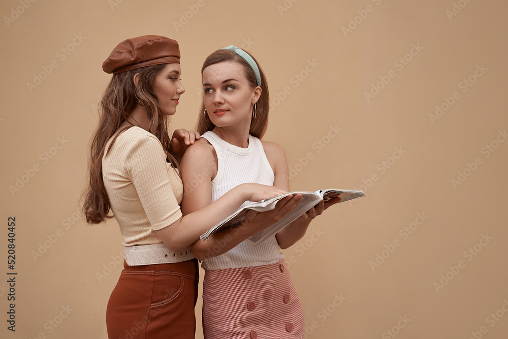 Young beautiful models dressed in retro vintage style enjoying the old european city summertime lifestyle reading a magazine. Old fashioned clothes.
