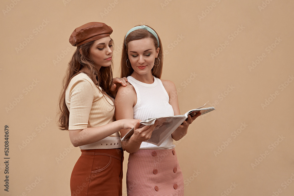 Young beautiful models dressed in retro vintage style enjoying the old european city summertime lifestyle reading a magazine. Old fashioned clothes.