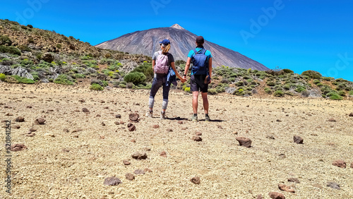 Couple on La Canada de los Guancheros dry desert plain with view on volcano Pico del Teide, Mount El Teide National Park, Tenerife, Canary Islands, Spain, Europe. Hiking to Riscos de la Fortaleza photo