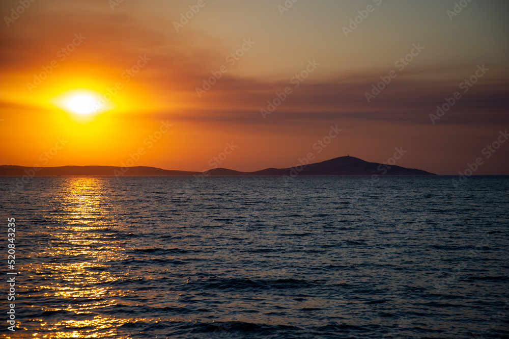 Sea and orange sky at sunset. Holiday landscape. Sun rays reflecting on the sea.