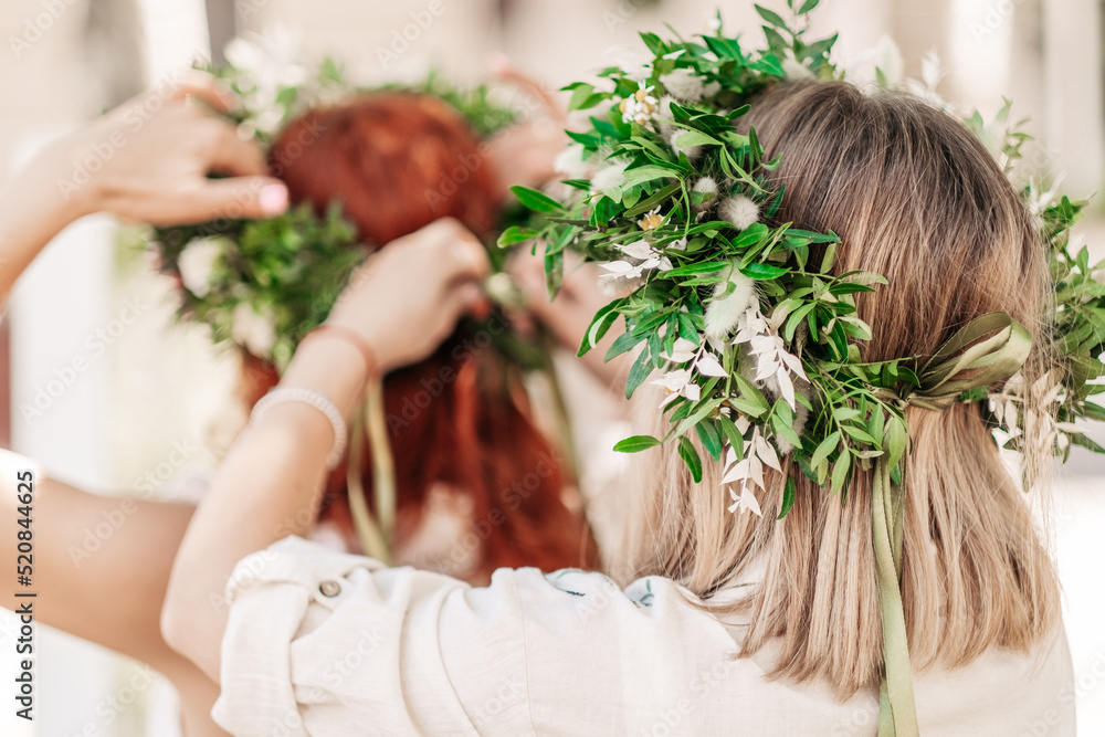 Obraz premium beautiful girl in wreath of flowers in meadow on sunny day. Portrait of Young beautiful woman wearing a wreath of wild flowers. Young pagan Slavic girl conduct ceremony on Midsummer. Earth Day