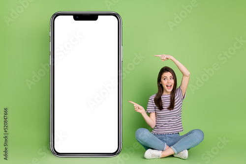Full size photo of amazed excited lady look direct fingers empty space blank isolated on green color background photo