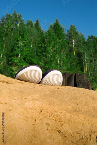 Close-up of a white sole sneaker on a rock in the forest with a backpack. concept of travel  vacation away from civilization