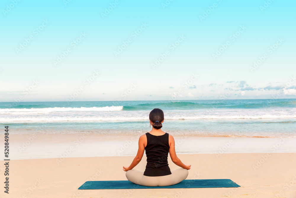 Fototapeta premium woman practicing yoga at seashore of tropic beach,Sports lady standing at the beach make yoga exercises