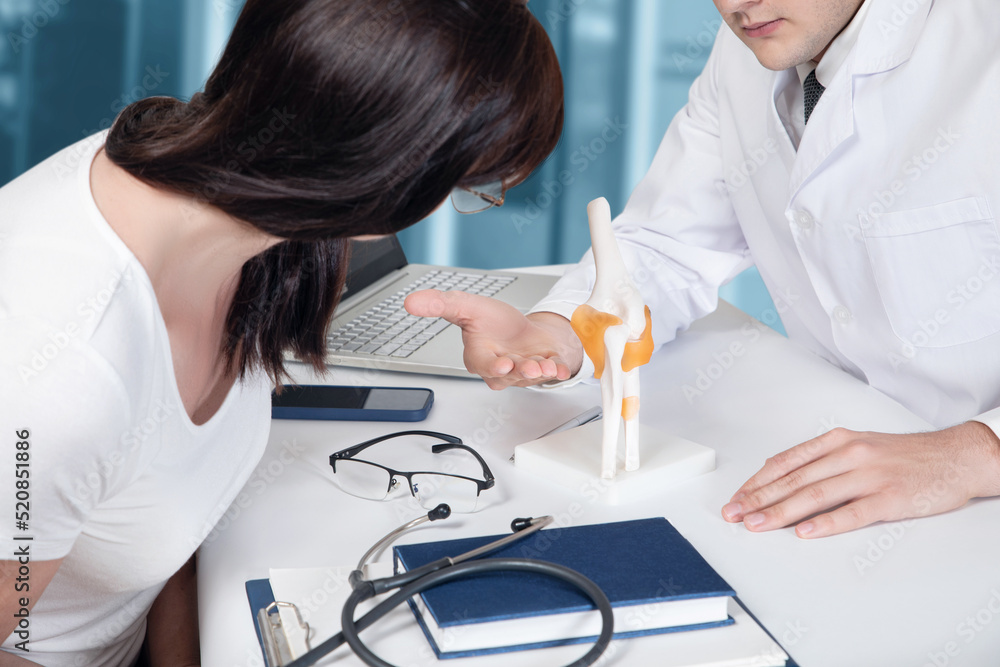 Doctor showing patient joint disease on model . Doctor showing patient joint disease on model .