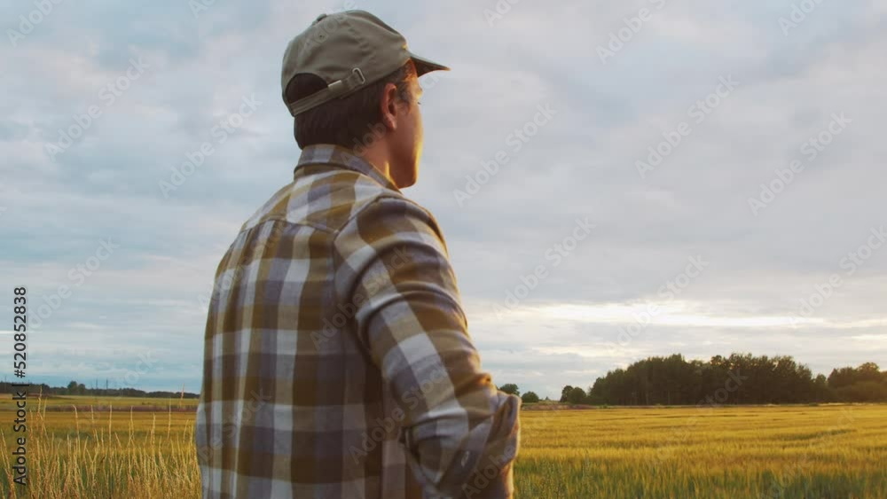 Farmer in front of a sunset agricultural landscape. Man in a countryside field. Country life, food production, farming and country lifestyle concept. Farmer in front of a sunset agricultural landscape. Man in a countryside field. Country life, food production, farming and country lifestyle concept.
