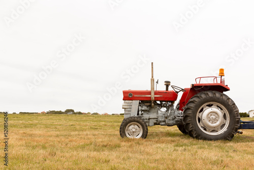 Side view of a tractor standing in a crop field. The day is cloudy. Concept of agriculture and rural life. Space for text. © Alfredo López