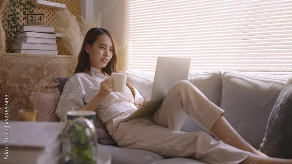 smiling asia girl use tablet shopping online,read news,chatting,browse wireless internet on gadget from home.Happy young asian woman relax on comfortable couch at home texting messaging on laptop. smiling asia girl use tablet shopping online,read news,chatting,browse wireless internet on gadget from home.Happy young asian woman relax on comfortable couch at home texting messaging on laptop.