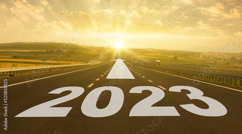 New year 2023 concept. Text 2023 written on the road in the middle of asphalt road at sunrise.