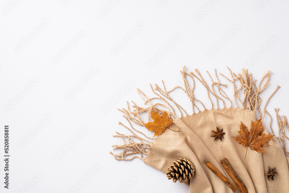 Obraz premium Autumn mood concept. Top view photo of cinnamon sticks yellow maple leaves anise and pine cone on beige scarf on isolated white background with copyspace
