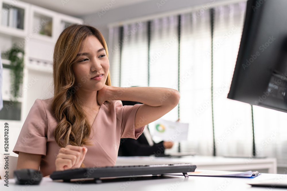 Asian employee woman massaging her neck and shoulder getting pain from office syndrome. Tensed muscles fatigued from working on computer in incorrect posture. health problem at workplace