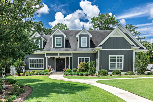 A large gray craftsman new construction house with a landscaped yard and leading pathway sidewalk photo