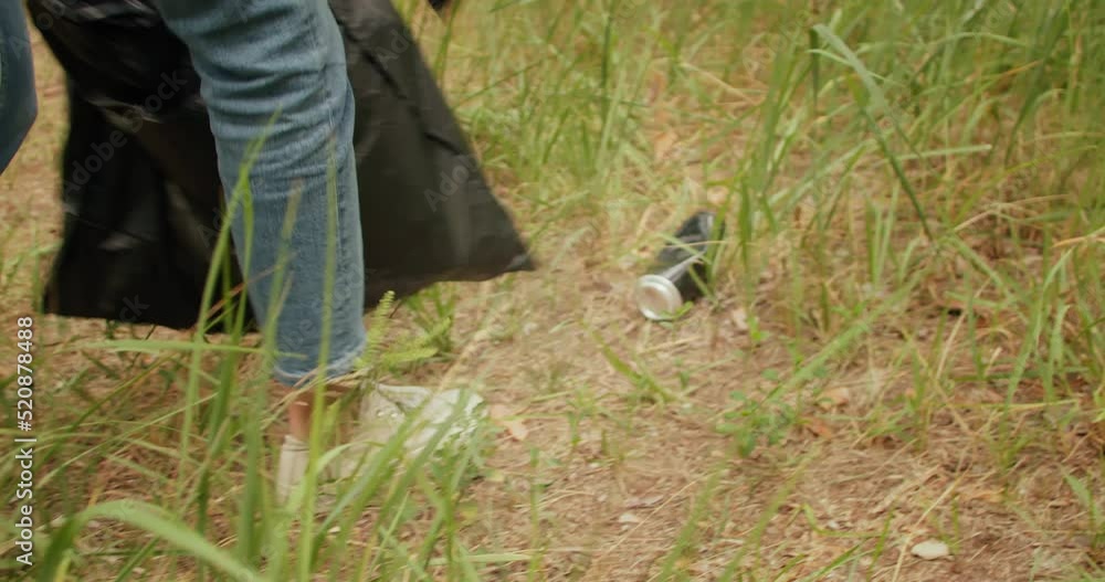 Woman cleaning nature from plastic garbage into trash bag. Collecting plastic bottle in forest Woman cleaning nature from plastic garbage into trash bag. Collecting plastic bottle in forest