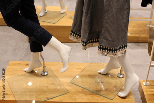 A mannequin stands on a showcase in a large store.
