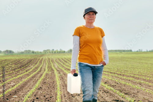 Corn crop protection concept, female farmer agronomist holding jerry can container canister with pesticide