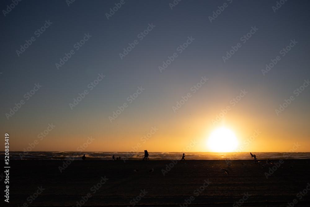 Fototapeta premium People at the beach during sunset