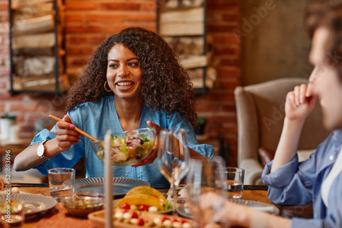 Portrait of beautiful black woman enjoying dinner party with friends in cozy setting