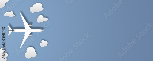Flat lay or table top picture of aircraft with clouds as paper cut outs. Airplane is to illustrate travel background. Picture has copy space, deign for mock up. Blue background. 