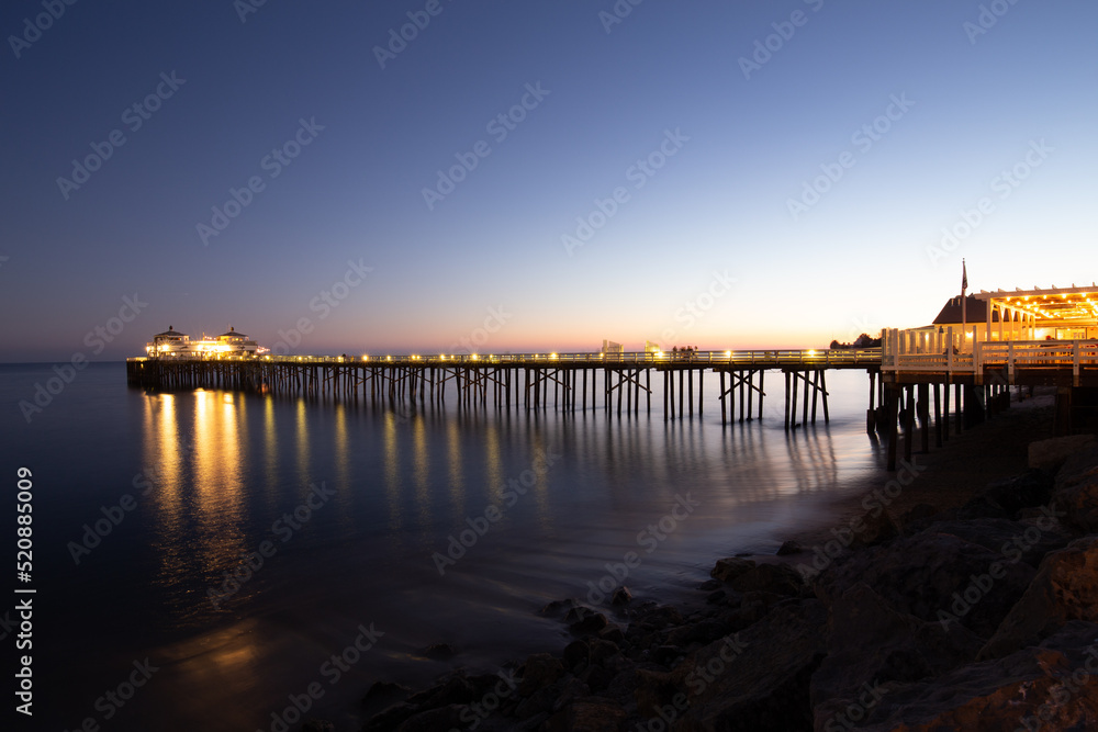 A pier over calm ocean at night