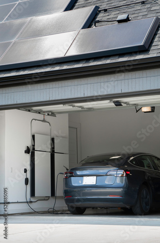 Solar Panels on a Roof Charging an Electric Vehicle and Home Battery Backup System in a Garage