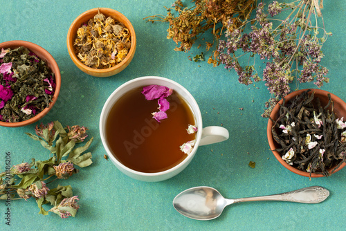 Herbal tea with flower petals and dried herbs in bunches and bowls