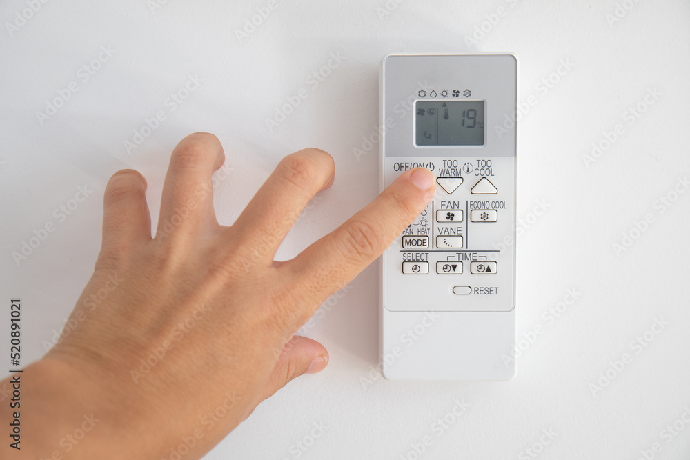 Hand turning on an air conditioning control, where 19 degrees are seen on the screen, as recommended by the new regulations of the Spanish government for winter Hand turning on an air conditioning control, where 19 degrees are seen on the screen, as recommended by the new regulations of the Spanish government for winter
