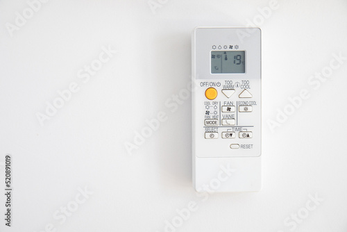 Air conditioner control hanging on a white wall, with 19 degrees on the display, as recommended by Spanish regulations for winter. Copy space