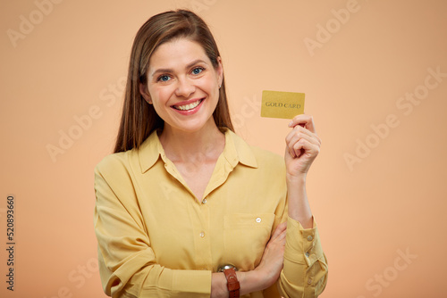Smiling woman holding credit card, isolated portrat on studio yellow background. photo