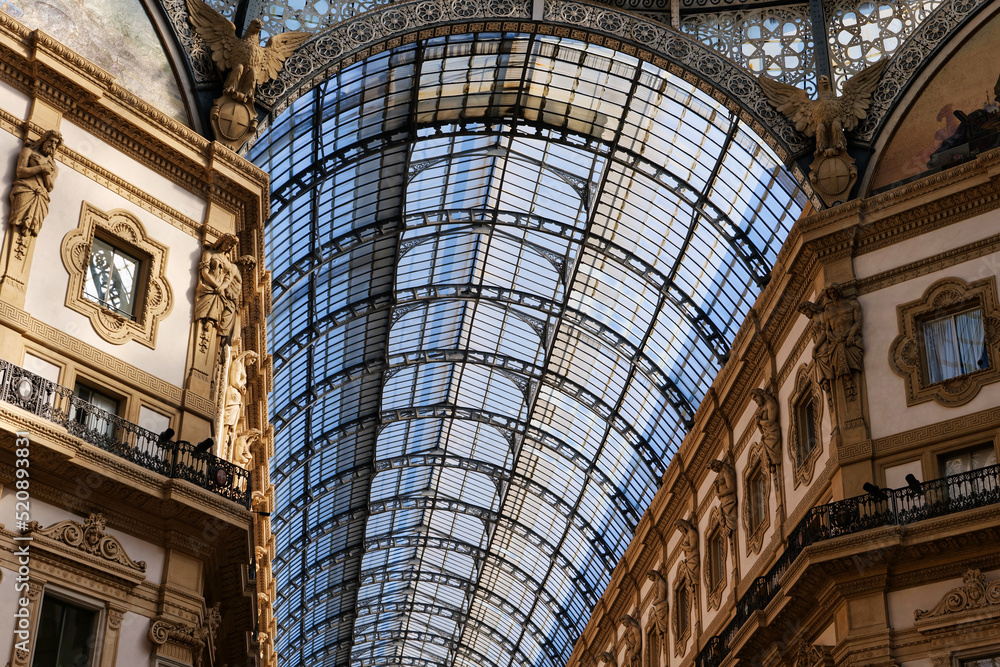 The roof and nicely decorated wall walls of Galleria Vittorio Emanuele in Milan, Italy. 19th-century building roof construction. Historical Italian building. Traditional steelwork roof. 