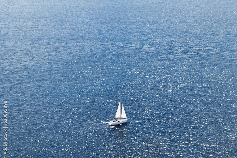 Arial photo of a sailboat cruising across the dark blue ocean. Yacht on the open sea. Yacht from above