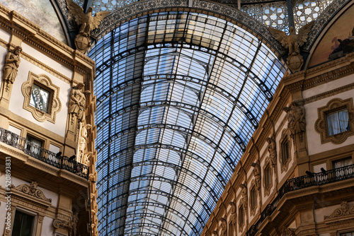 The roof and nicely decorated wall walls of Galleria Vittorio Emanuele in Milan, Italy. 19th-century building roof construction. Historical Italian building. Traditional steelwork roof.  #520893831