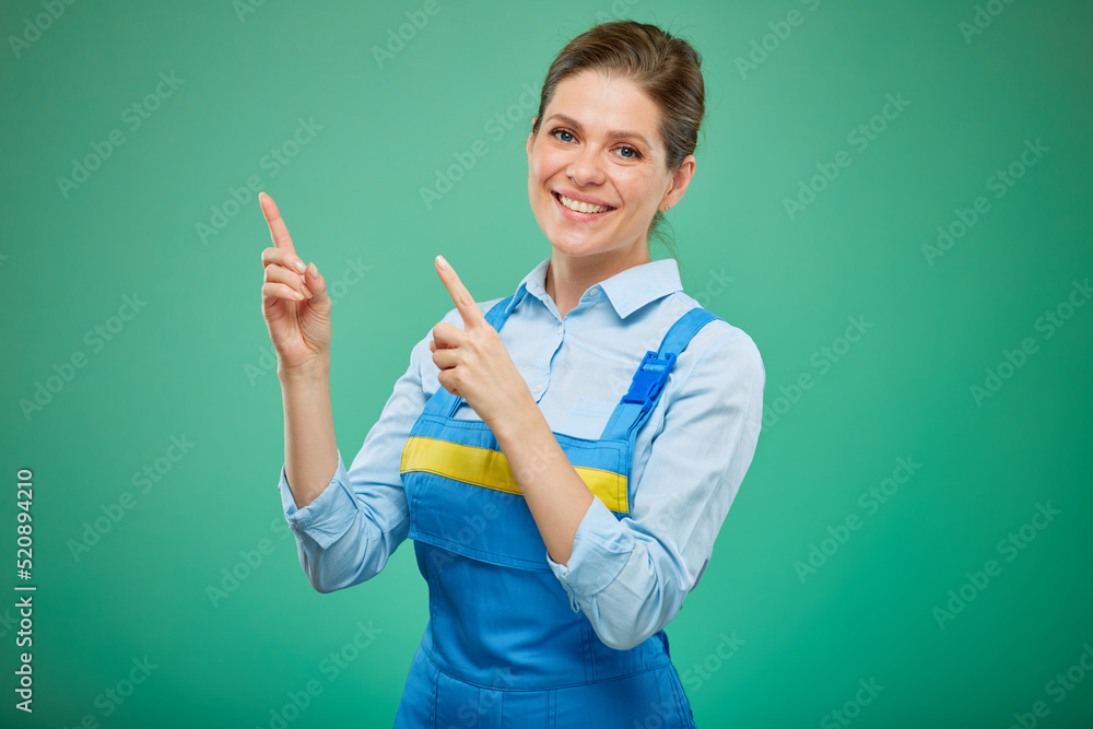 smiling woman in overalls pointing fingers up. isolated on green background. smiling woman in overalls pointing fingers up. isolated on green background.