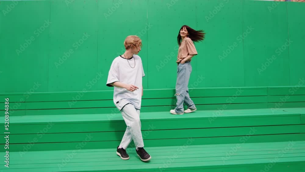 Young couple dancing hip hop on green background wall. Modern dance choreography. Professional dancers man and woman duet showing dance movings. Musical video. Young couple dancing hip hop on green background wall. Modern dance choreography. Professional dancers man and woman duet showing dance movings. Musical video.