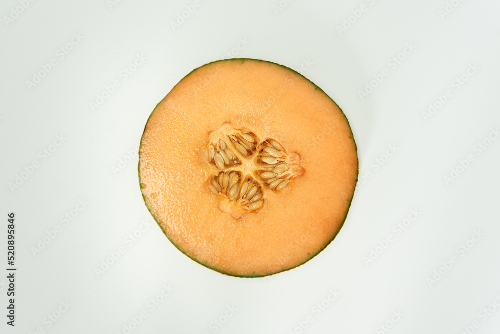 Single cantaloupe slice and seeds in center of white background top view