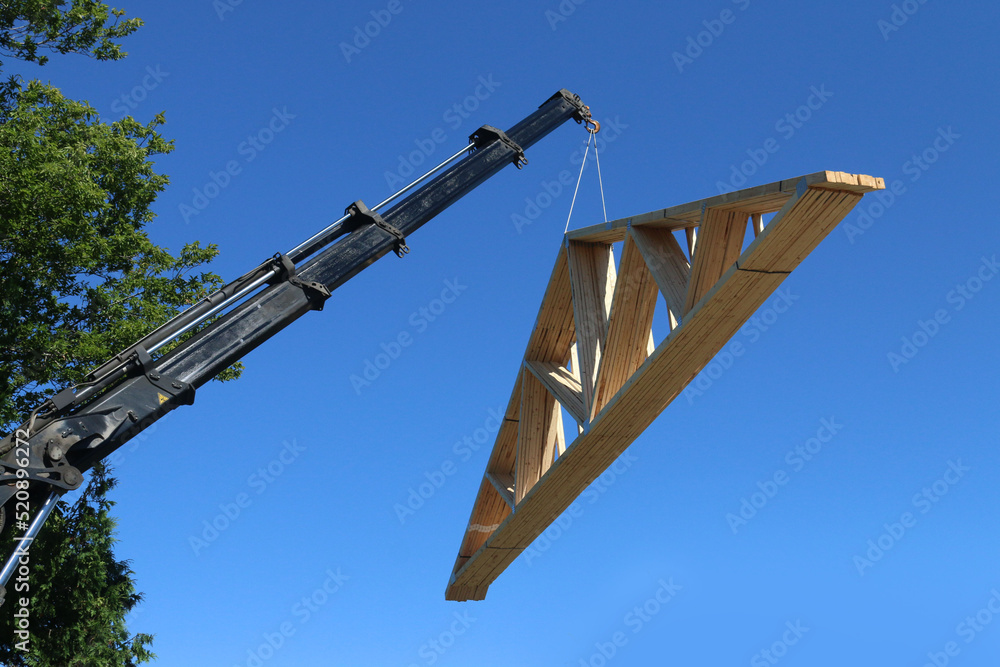 Lifting roof trusses by truckmounted crane on hot summer day Stock