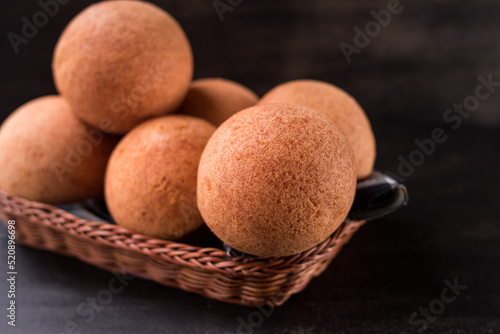 Round colombian traditional food named buñuelo in a basket on black wooden table  photo