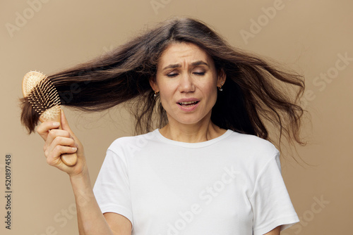 a sad sad upset woman stands in a white T-shirt with a wooden comb stuck in her long dark hair